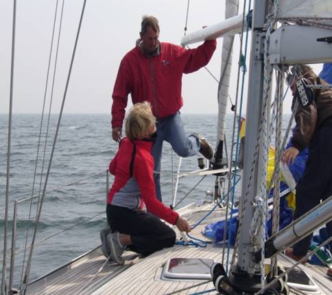 zeezeilinstructeur legt het gebruik van de spinnaker boom uit zodat de spinnaker zo gezet kan worden tijdens de zeiltocht